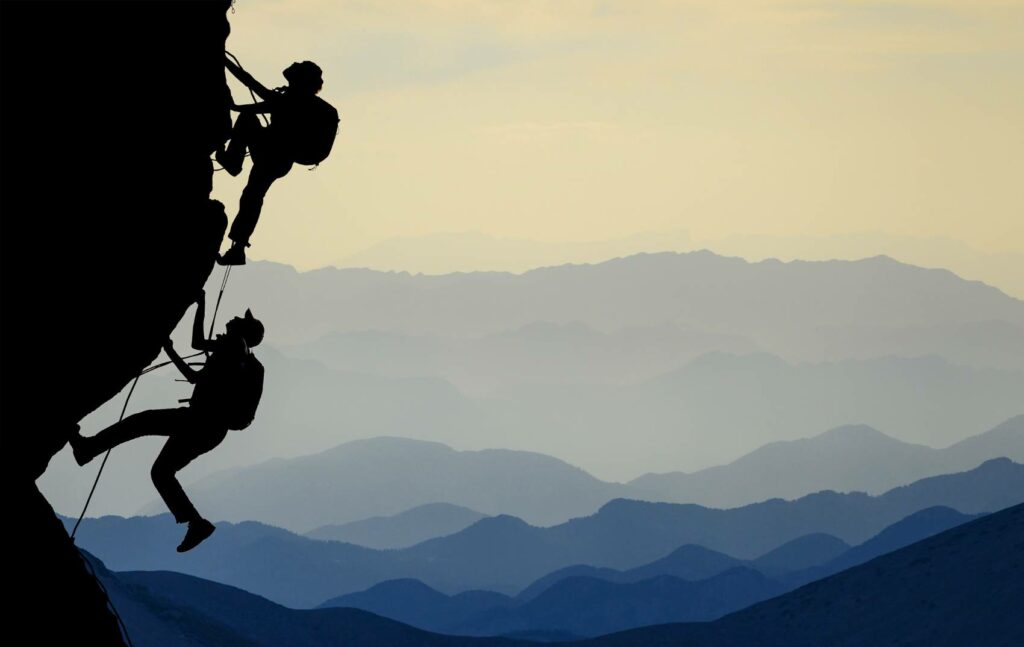 Two people climbing a mountain