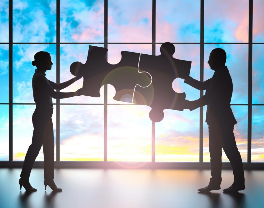 Two people joining 2 pieces of a puzzle