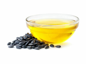 Dark colored seeds beside a bowl of oil.