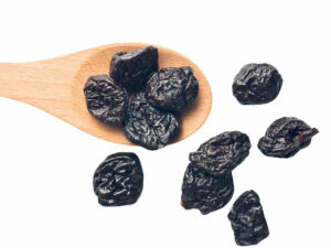 Dried Prunes displayed with a wooden spoon.