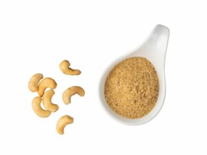 Cashew Flour beside cashews on a ceramic spoon