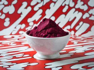 Beetroot powder on a white bowl with a pop art red & white background.