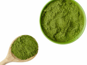 Top view of green powder in a bowl and on a wooden spoon,