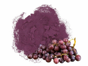Vibrant, purple powder in a heap displayed with some grapes.
