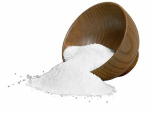 Heap of white powder beside a wooden bowl of the white powder.