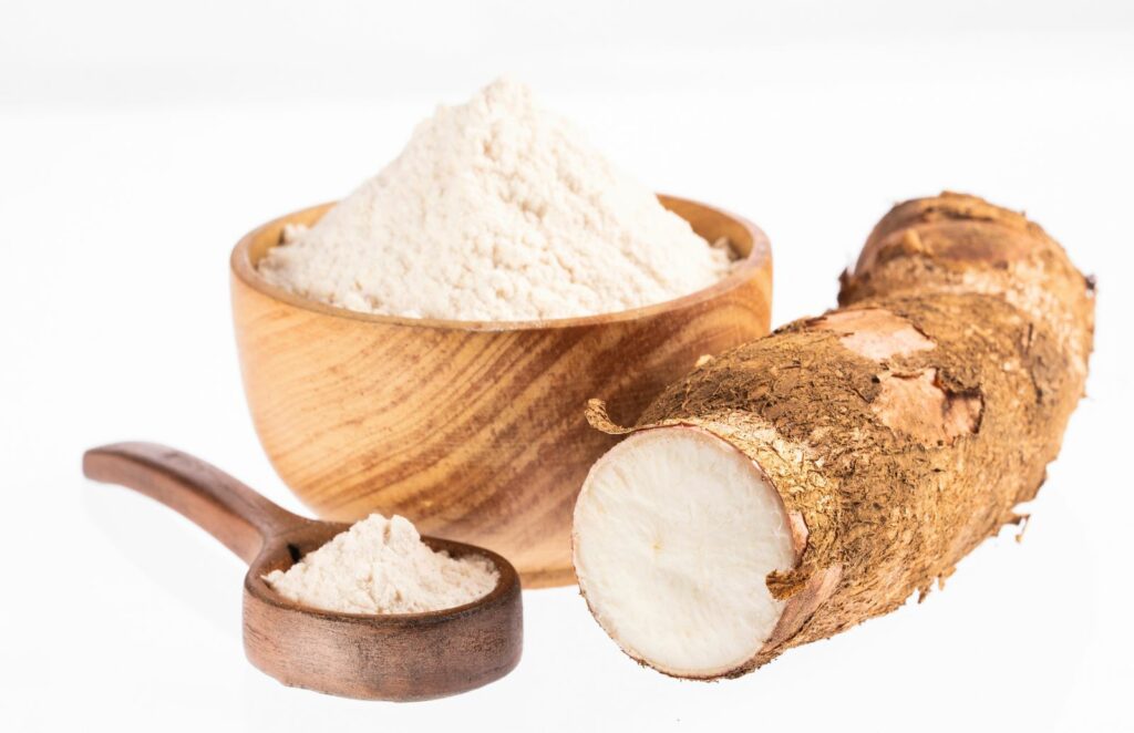 arrowroot powder in a wooden bowl and a wooden spoon on a white background
