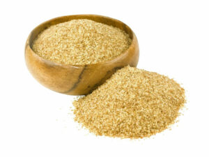Brown meal in a wooden bowl displayed beside a heap of brown meal.