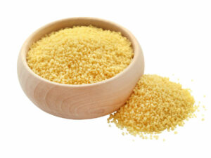 Couscous in a wooden bowl displayed beside a heap of couscous