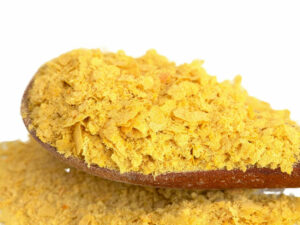 Golden flakes displayed on a wooden spoon.