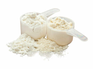 Two measuring cups filled with a white powder beside a hap of white powder.