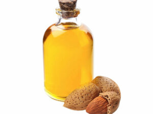 Bottle of oil beside some almond nuts.