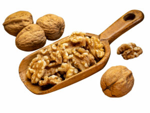 Shelled walnuts surrounding unshelled walnuts displayed on a wooden spoon.