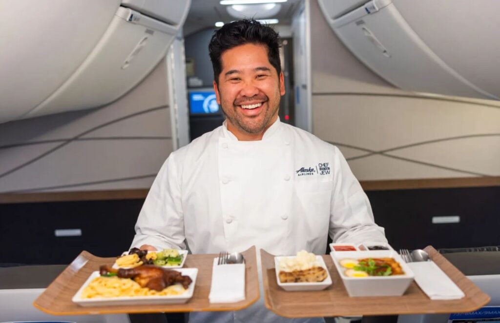 A man holding a tray of food on a plane.