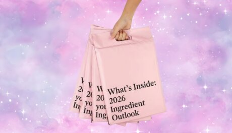 A hand holding several pink envelopes, one of which is open and displays the text "What's Inside: 2026 Ingredient Outlook."