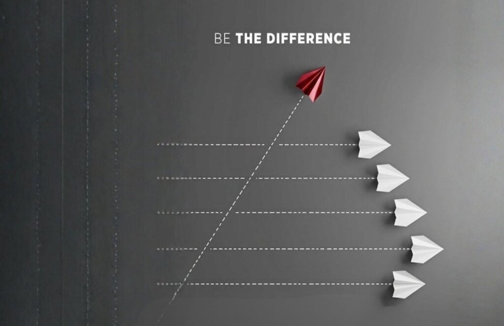 An image of 5 white airplanes going on 1 direction and a Red one in a different one and a sign that says "Be The Difference"