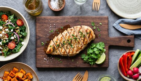 Flatlay of grilled chicken breast with fresh vegetables